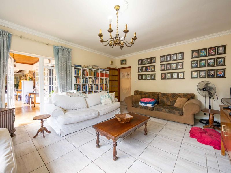 A spacious living room featuring tiled flooring, decorative ceiling cornice, and classic french doors leading to an adjacent area.