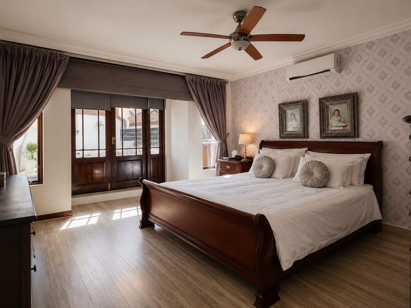 A well-maintained bedroom featuring laminate flooring, crown molding, a ceiling fan, and a split-system air conditioner, with direct access to an outdoor area.