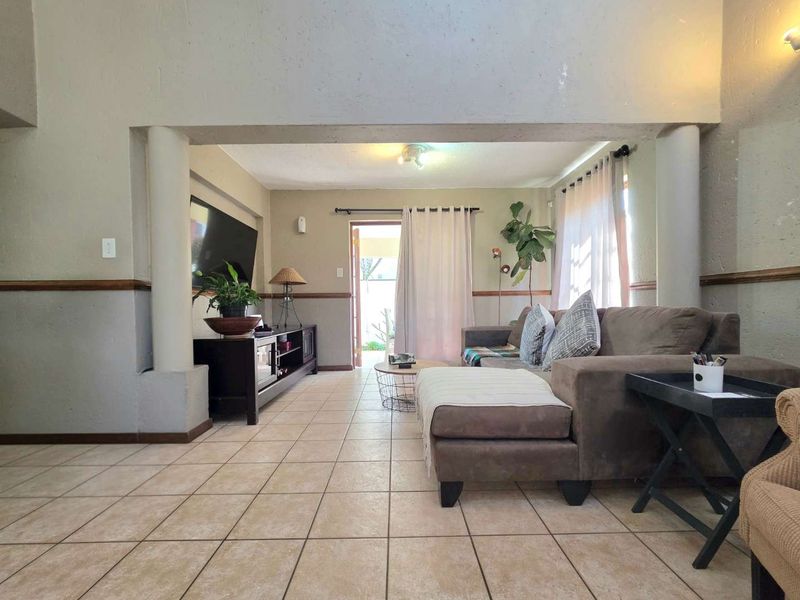 Spacious living room featuring ceramic floor tiles, structural columns, and a sliding door providing access to the outdoor area.