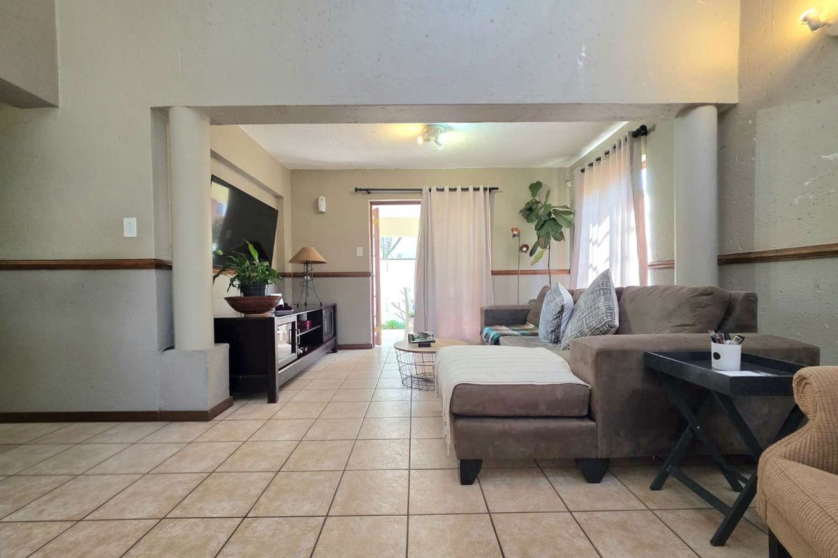 Spacious living room featuring ceramic floor tiles, structural columns, and a sliding door providing access to the outdoor area.
