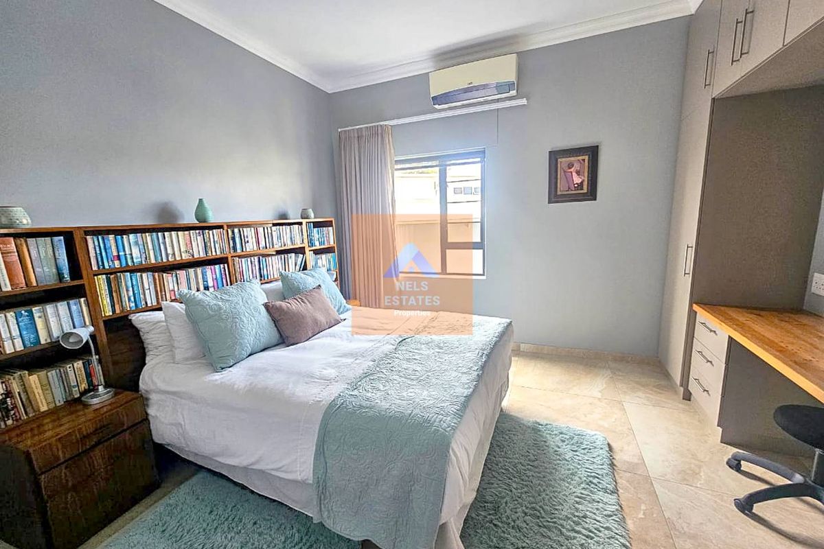 A well-maintained bedroom featuring tiled flooring, built-in cabinetry with a desk area, and a wall-mounted air conditioning unit.