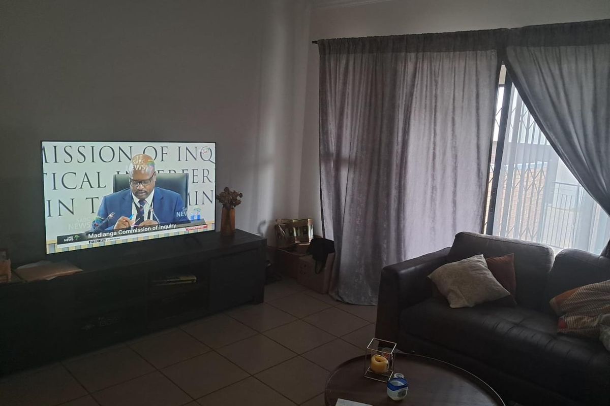 A living room featuring tiled flooring and a sliding door leading to a balcony, providing natural light to the space.