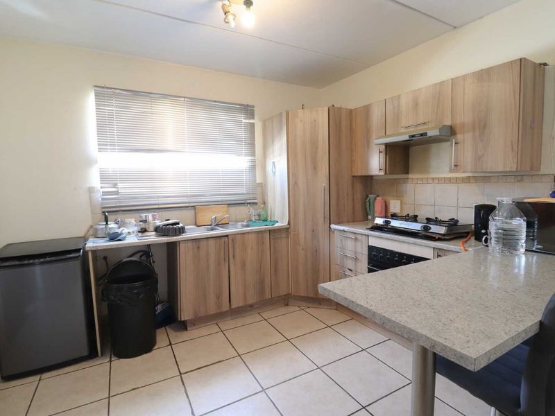 Functional kitchen featuring laminate cabinetry, stone-look countertops, built-in oven with gas hob, extractor fan, and tiled flooring.
