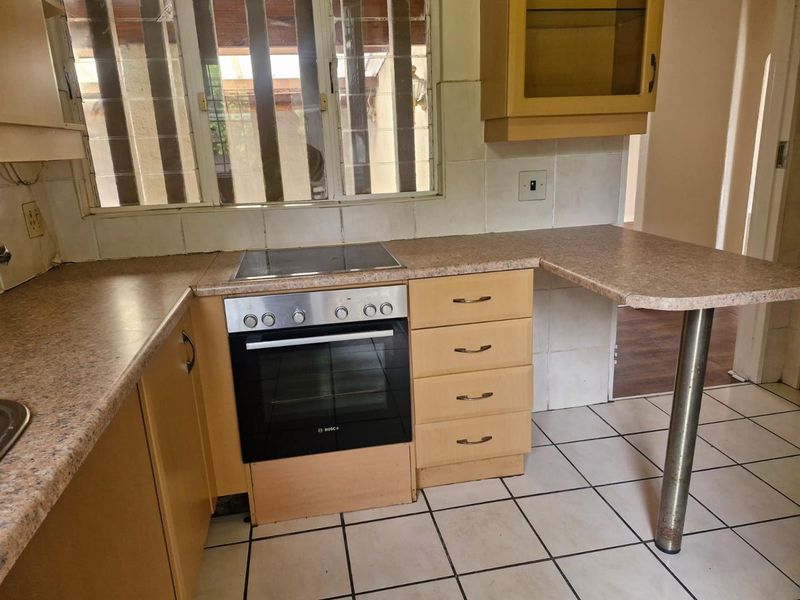 A functional kitchen featuring laminate countertops, built-in oven and hob, tiled flooring, and ample cabinetry, offering a solid foundation for a modern renovation.