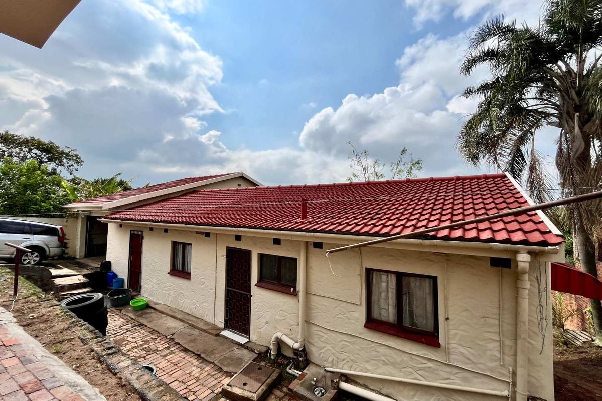 Rear view of the house featuring a tiled roof, brick paved walkway, and exterior wall access points.