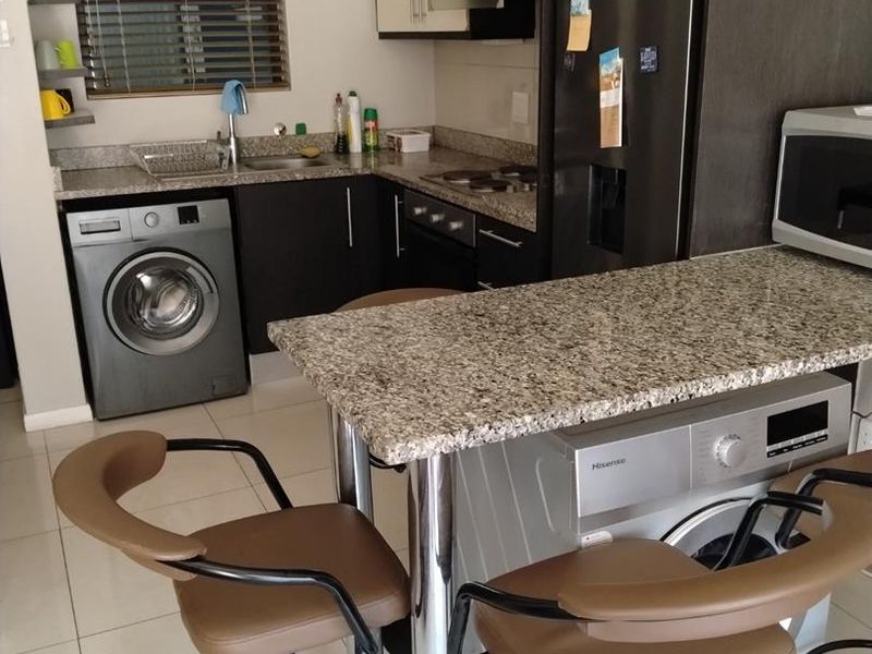 Compact kitchen featuring granite countertops, built-in cabinetry, integrated appliances, and a breakfast bar, providing a functional and efficient cooking and dining space.