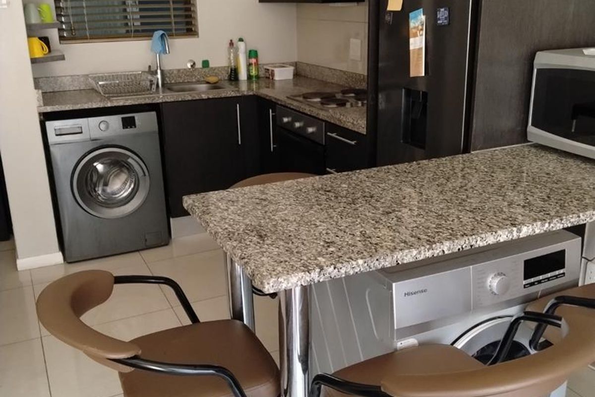 Compact kitchen featuring granite countertops, built-in cabinetry, integrated appliances, and a breakfast bar, providing a functional and efficient cooking and dining space.