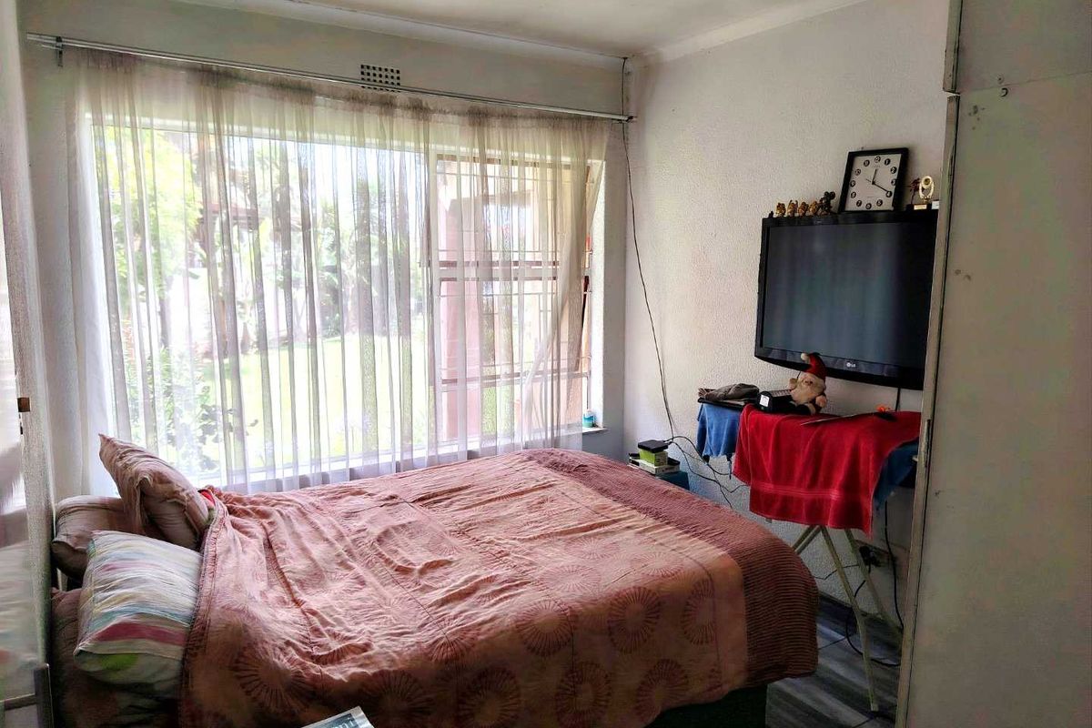 A bedroom featuring a large window with natural light, tiled flooring, and built-in cupboard space.