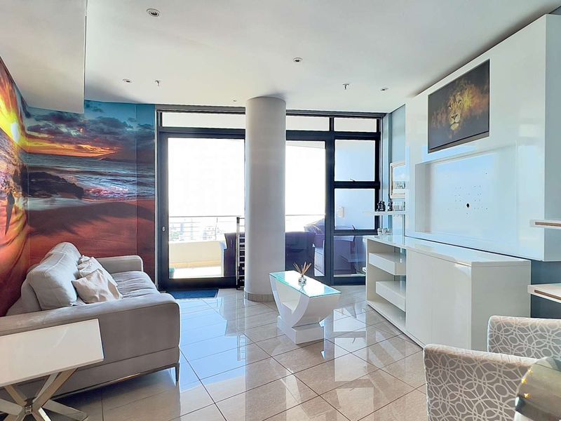 Modern living room featuring polished tile flooring, a built-in media console, and large sliding glass doors providing access to the balcony.