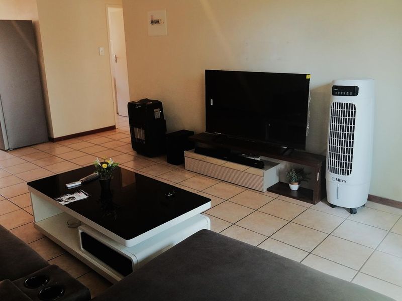 A living room area featuring neutral wall finishes and tiled flooring throughout.