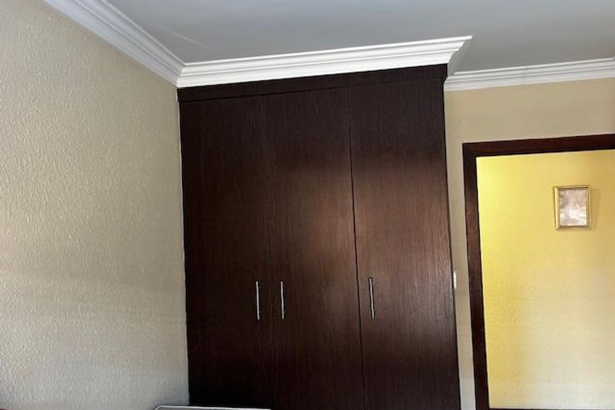 A bedroom featuring built-in dark wood cabinetry with crown molding detail, providing ample storage space.