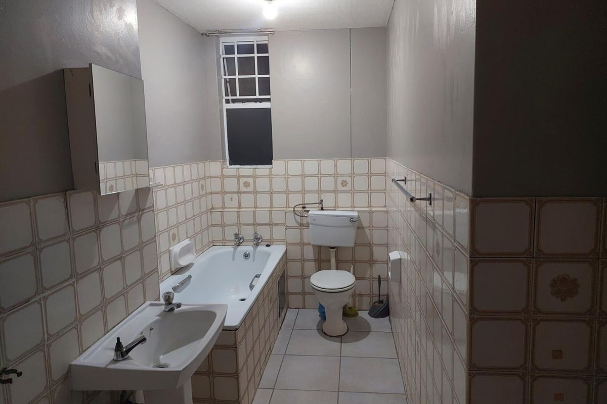 A functional bathroom featuring a pedestal basin, bathtub, and toilet with classic tiled walls and flooring.