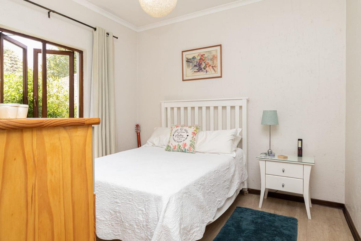 A cozy bedroom featuring a casement window with garden views and neutral wall finishes.