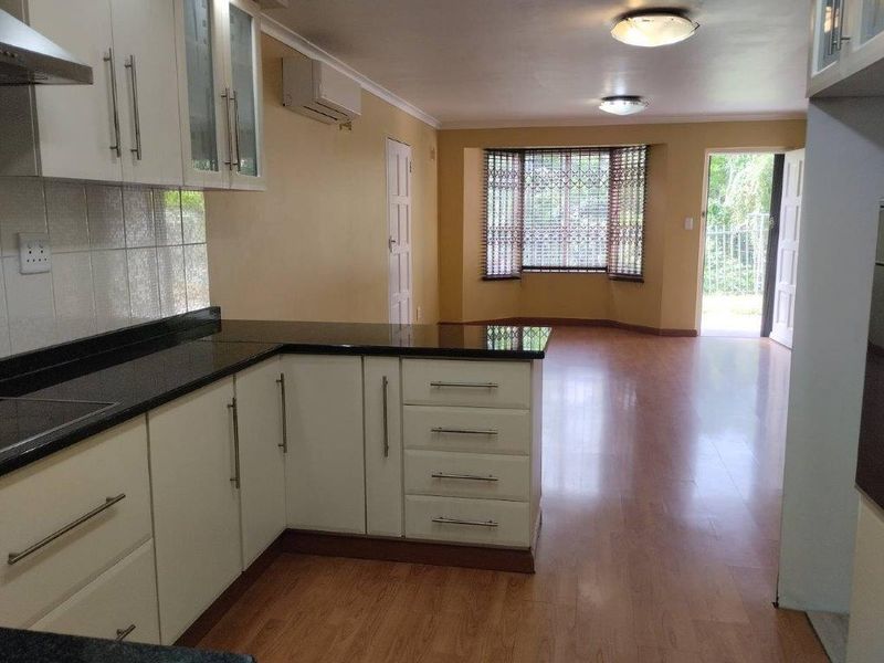 Spacious open-plan kitchen and living area featuring laminate flooring, modern cabinetry with granite countertops, and direct access to the exterior.