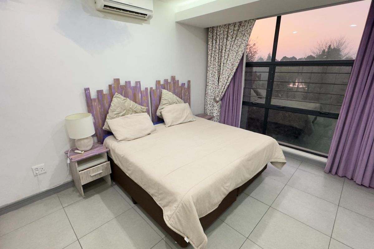 A bedroom featuring large floor-to-ceiling windows with integrated security bars, tiled flooring, and a wall-mounted air conditioning unit.