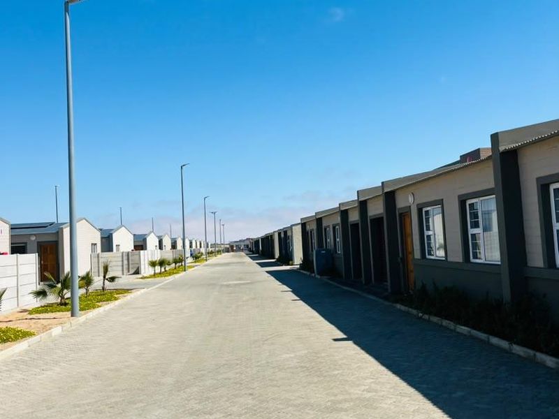 A clear street view of a modern townhouse development featuring paved driveways, uniform exterior facades, and established street lighting.