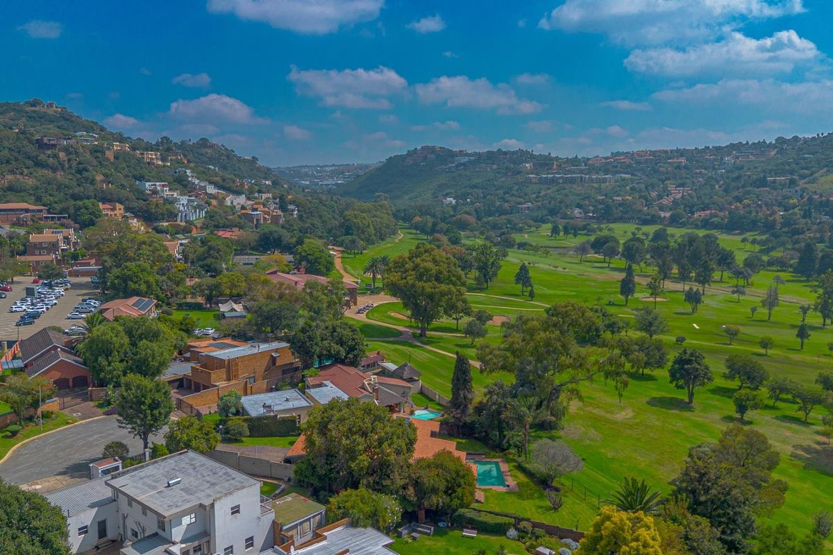 Aerial view of a residential property situated adjacent to a lush green golf course, showcasing the surrounding landscape and estate layout.