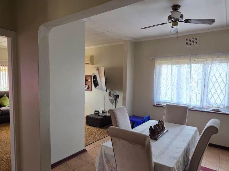 Open-plan living and dining area featuring tiled and carpeted flooring, a ceiling fan, and an air conditioning unit.