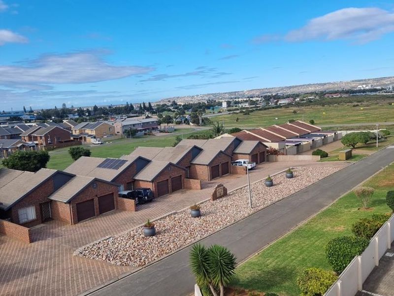 An elevated aerial view of a residential apartment complex featuring brick-faced units, paved driveways, and well-maintained communal garden areas.