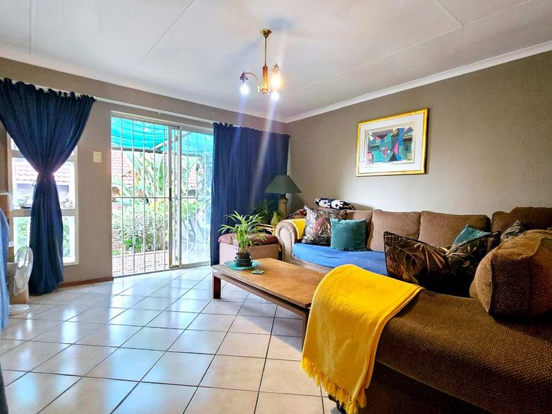 A comfortable living room featuring tiled flooring and a sliding glass door that provides access to the outdoor area.