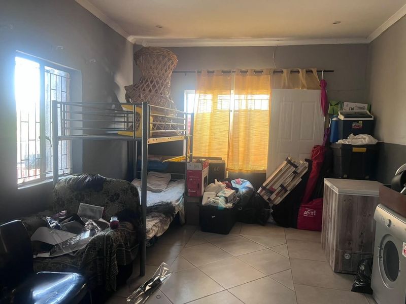 A bedroom featuring tiled flooring and security bars on the windows, currently in need of maintenance and cosmetic updates.