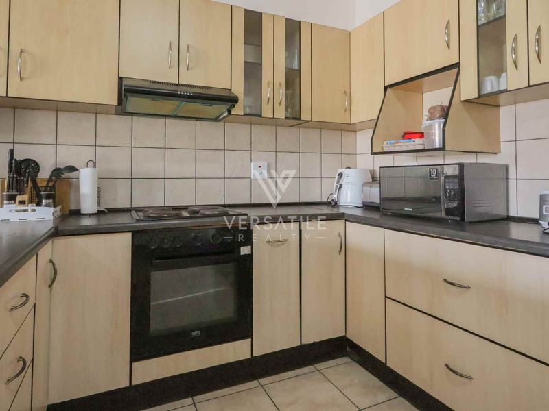 A functional kitchen featuring light wood-tone cabinetry, dark laminate countertops, a built-in oven, and a tiled backsplash.