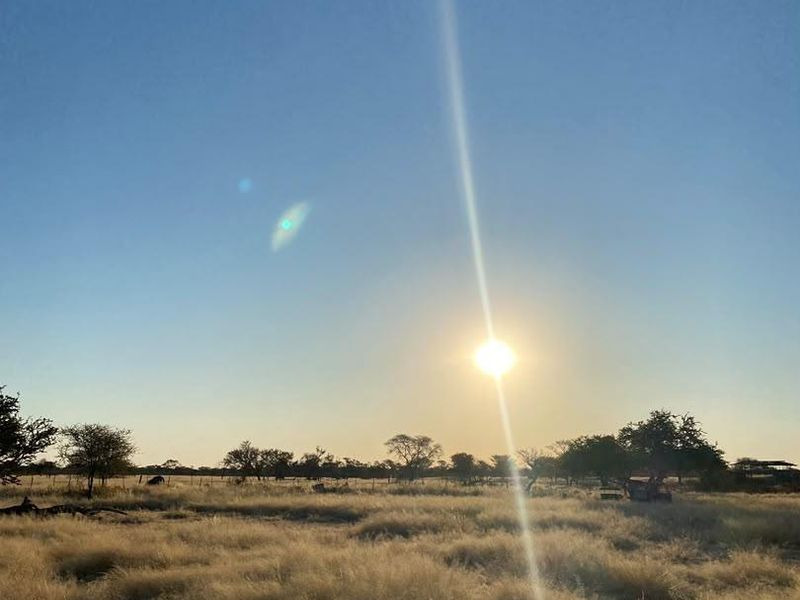 A scenic view of the open farm landscape at sunset, showcasing the natural terrain and vegetation.
