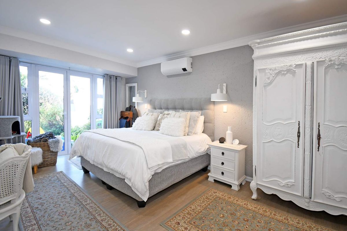 Spacious bedroom featuring recessed lighting, wall-mounted air conditioning unit, and glass sliding doors providing direct access to the outdoor area.