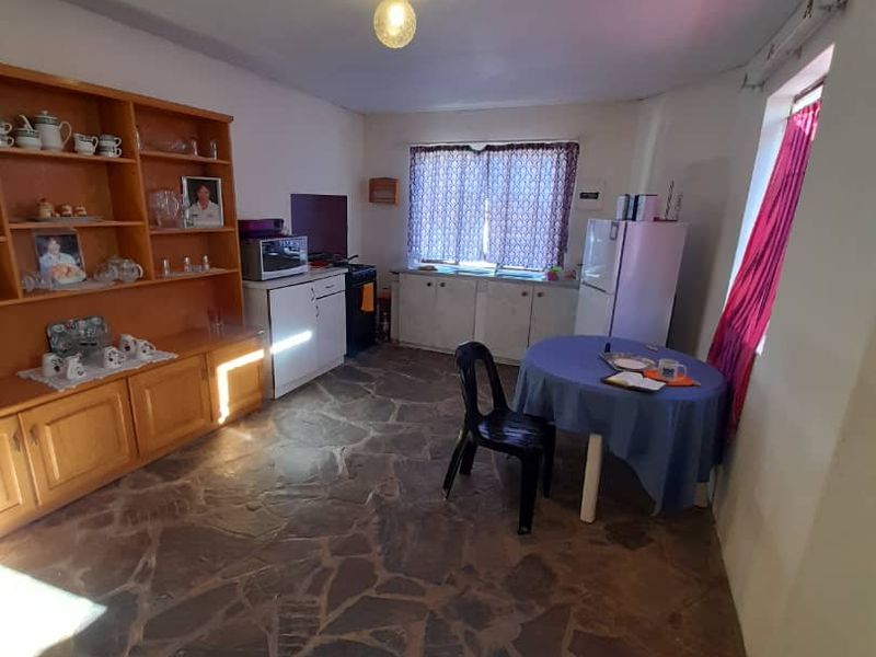 A functional kitchen area featuring stone flooring and built-in cabinetry, offering a dated aesthetic with potential for modernization.