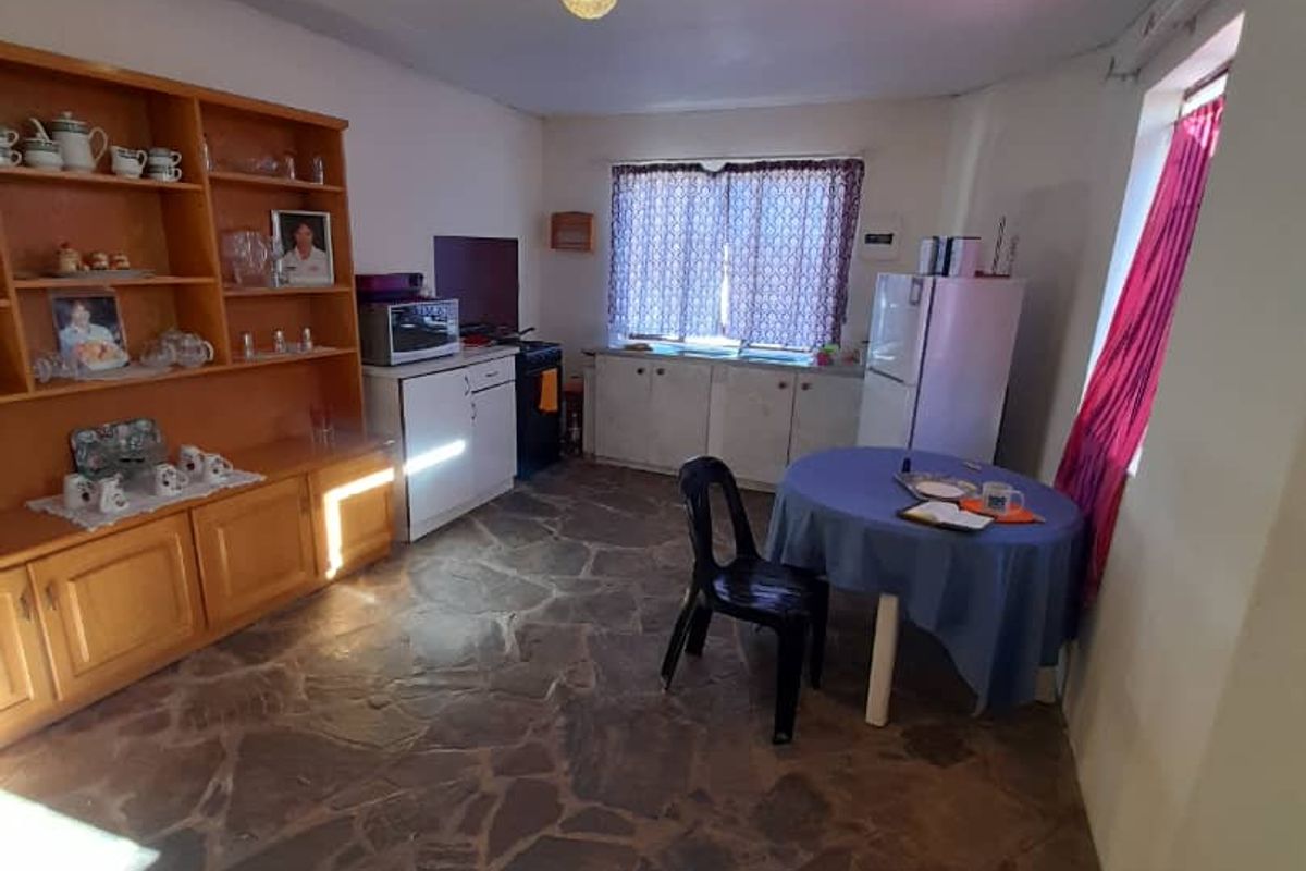 A functional kitchen area featuring stone flooring and built-in cabinetry, offering a dated aesthetic with potential for modernization.