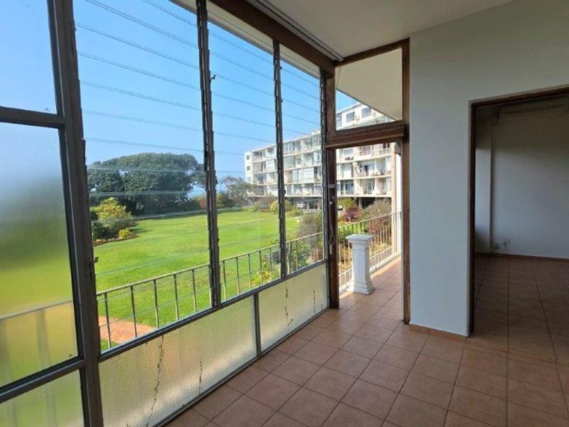 Enclosed balcony featuring tiled flooring and large louvre windows with views over the communal garden area.