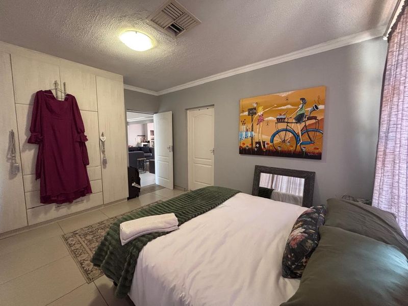 A functional bedroom featuring built-in cupboards, tiled flooring, and a ceiling fan, offering a neutral base for personalization.
