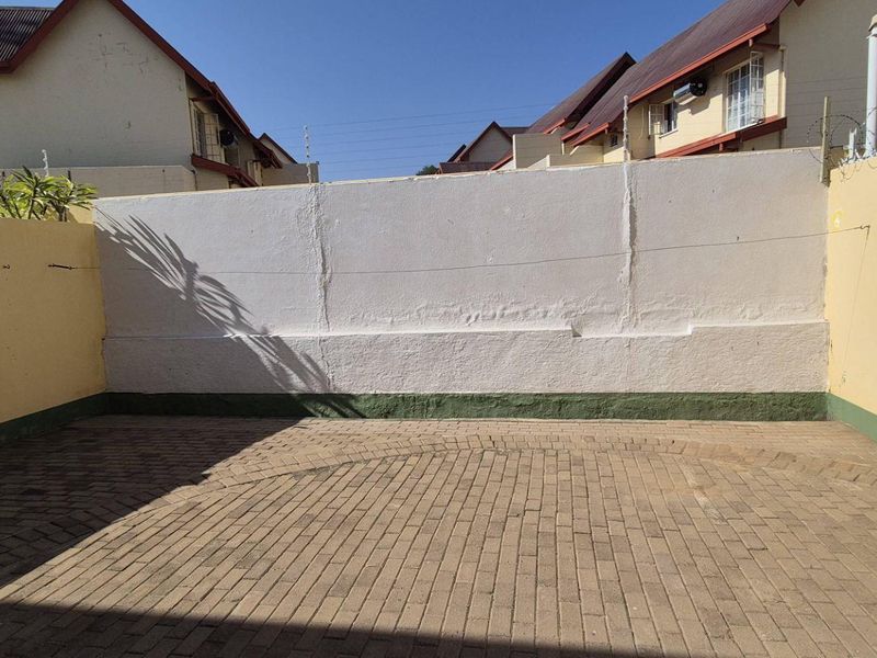 A private paved rear courtyard featuring high perimeter walls with security spikes, offering a secure and low-maintenance outdoor space.