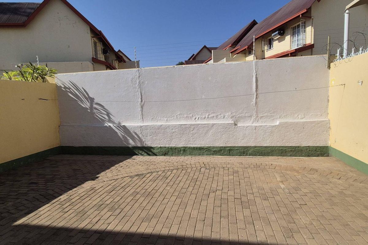 A private paved rear courtyard featuring high perimeter walls with security spikes, offering a secure and low-maintenance outdoor space.