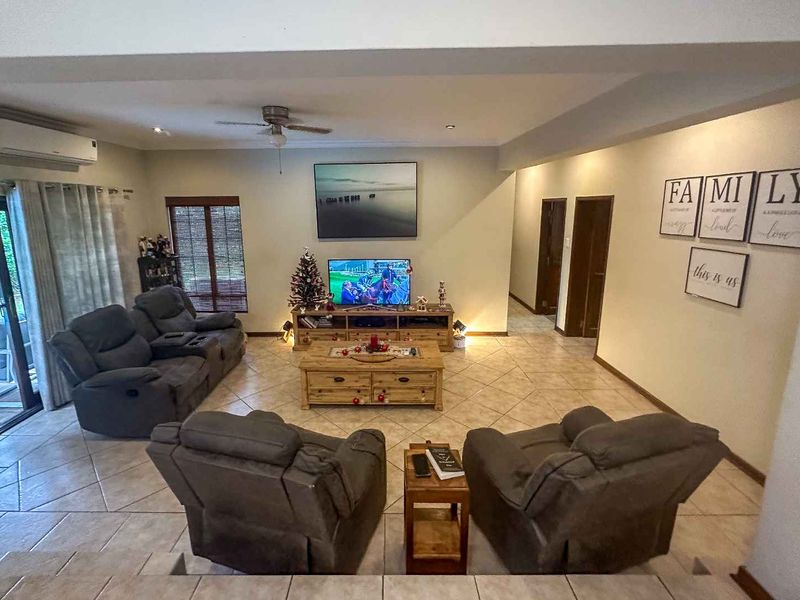 Spacious living room featuring tiled flooring, a ceiling fan, and a split-system air conditioner, with direct access to the outdoor patio area.