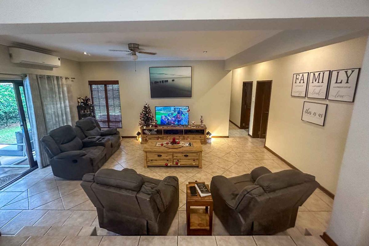 Spacious living room featuring tiled flooring, a ceiling fan, and a split-system air conditioner, with direct access to the outdoor patio area.