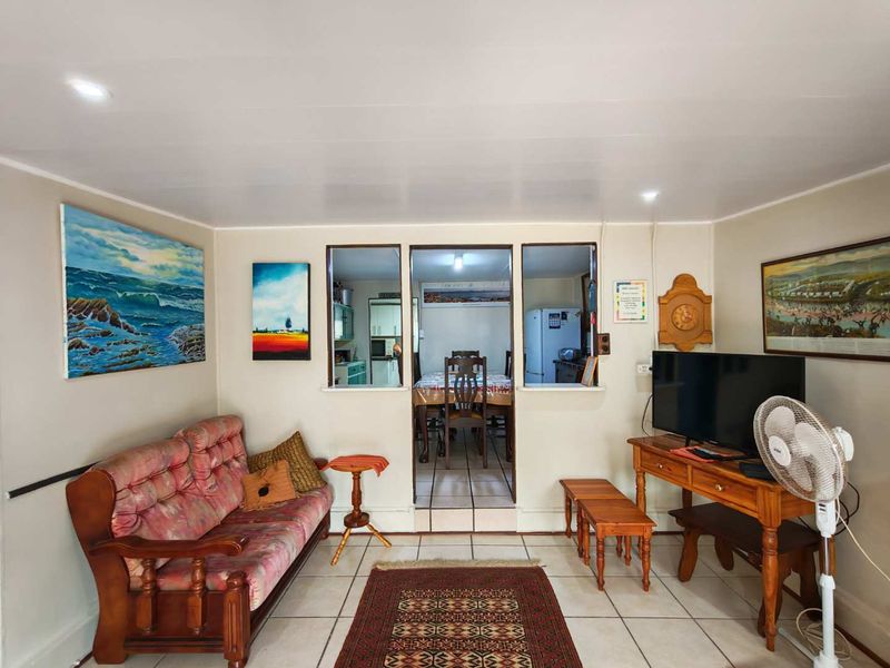 A living room featuring tiled flooring and a pass-through window connecting to the adjacent dining area.
