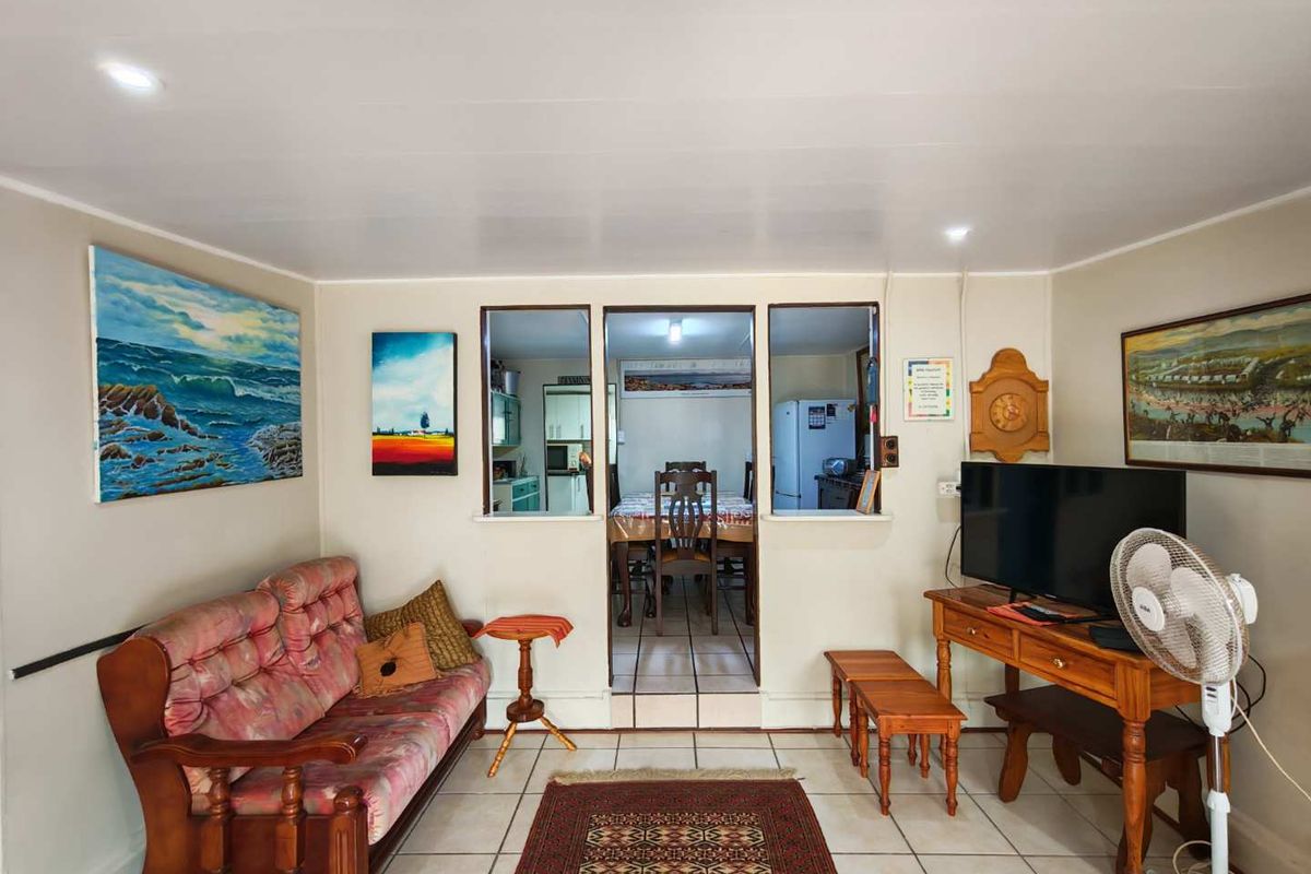 A living room featuring tiled flooring and a pass-through window connecting to the adjacent dining area.
