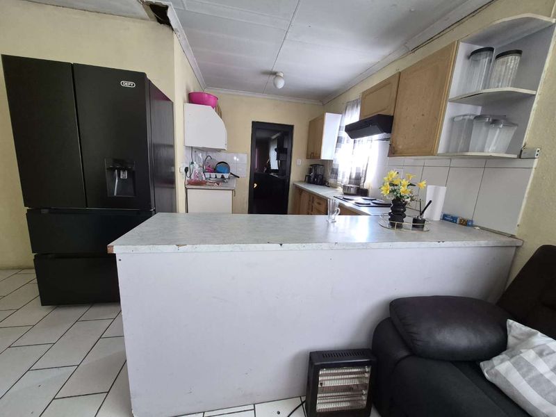 A dated kitchen featuring built-in cabinetry, a breakfast bar, and tiled flooring, currently showing signs of wear and ceiling damage.