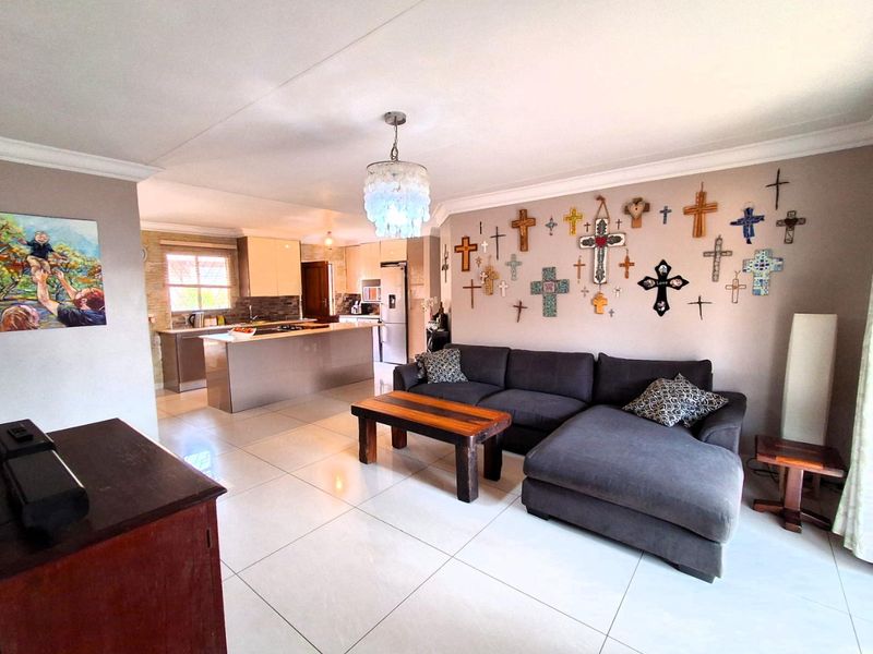 Open-plan living area featuring a modern kitchen with a central island, tiled flooring, and neutral wall finishes, creating a spacious and functional layout.