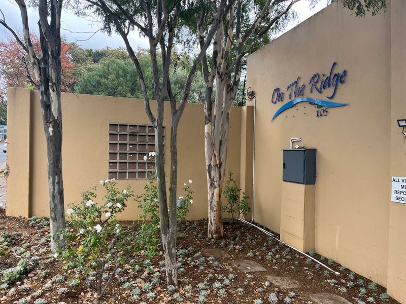 Front boundary wall of the On The Ridge apartment complex featuring integrated communal mailboxes and building signage.