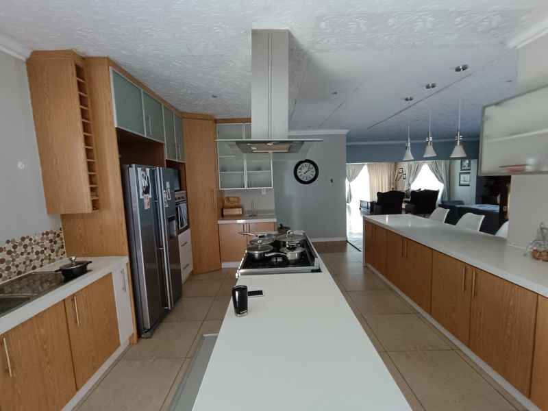 Spacious open-plan kitchen featuring a large central island, modern cabinetry, stainless steel appliances, and tiled flooring, flowing seamlessly into the adjacent living area.