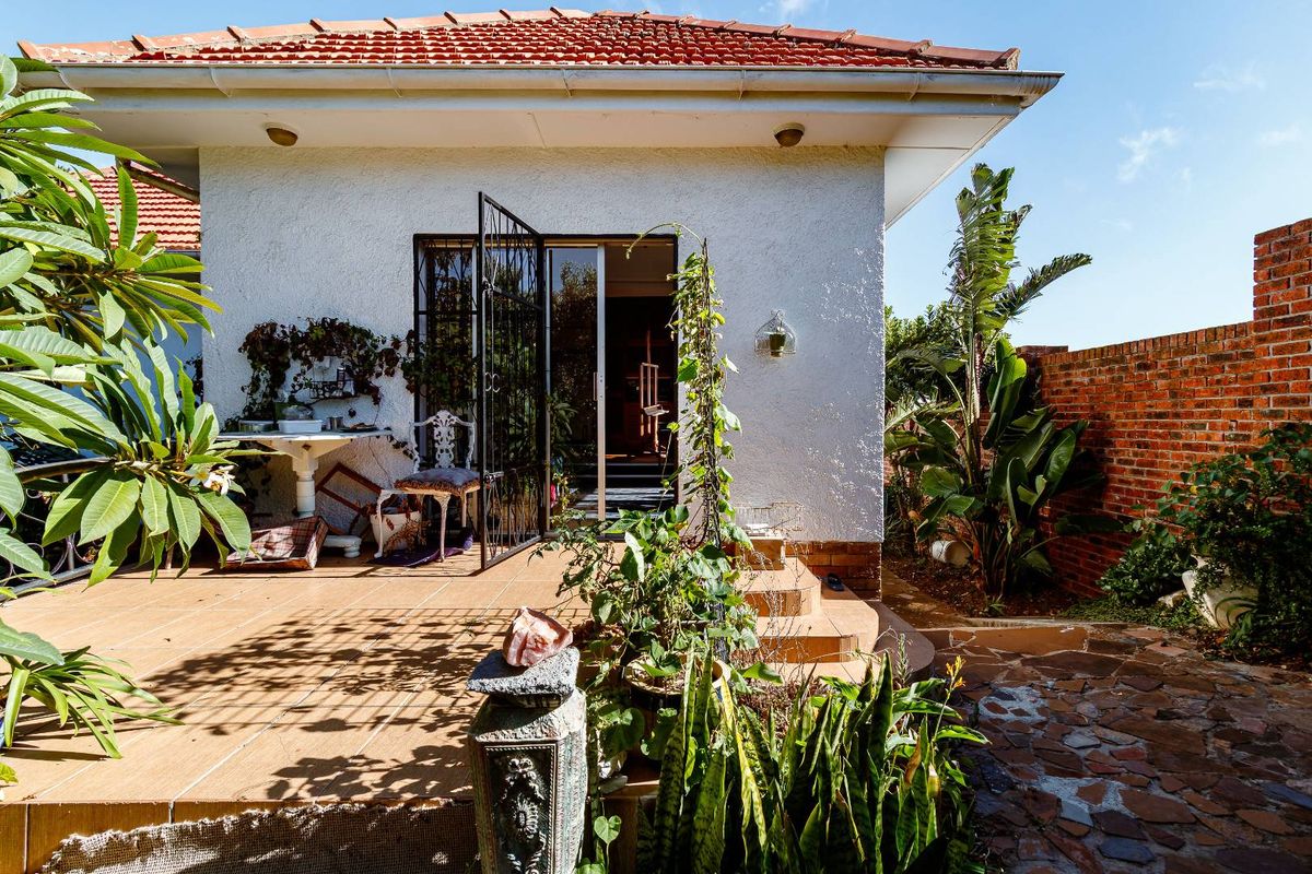 A rear patio area featuring tiled flooring, a security gate entrance, and a brick boundary wall, providing a private outdoor space.