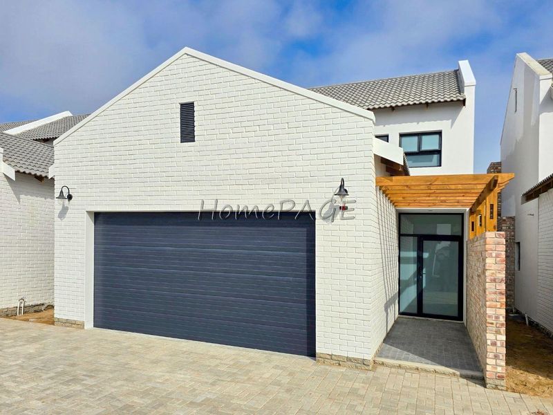 Modern townhouse exterior featuring a clean white brick facade, automated garage door, and a timber pergola over the entrance walkway.