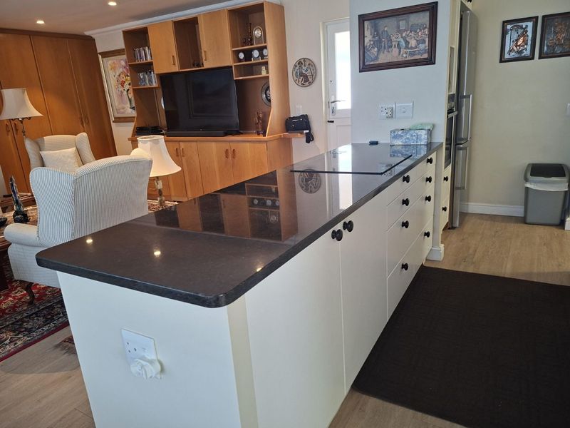 Open plan living area featuring a modern kitchen island with stone countertops, integrated cabinetry, and seamless flow into the adjacent living space.