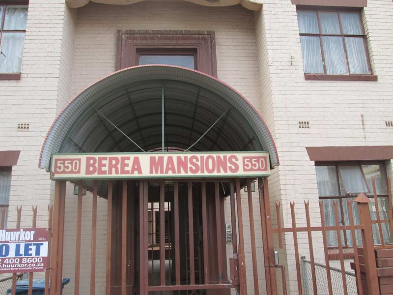 Front entrance of Berea Mansions featuring a brick facade, metal security gate, and a corrugated metal awning.