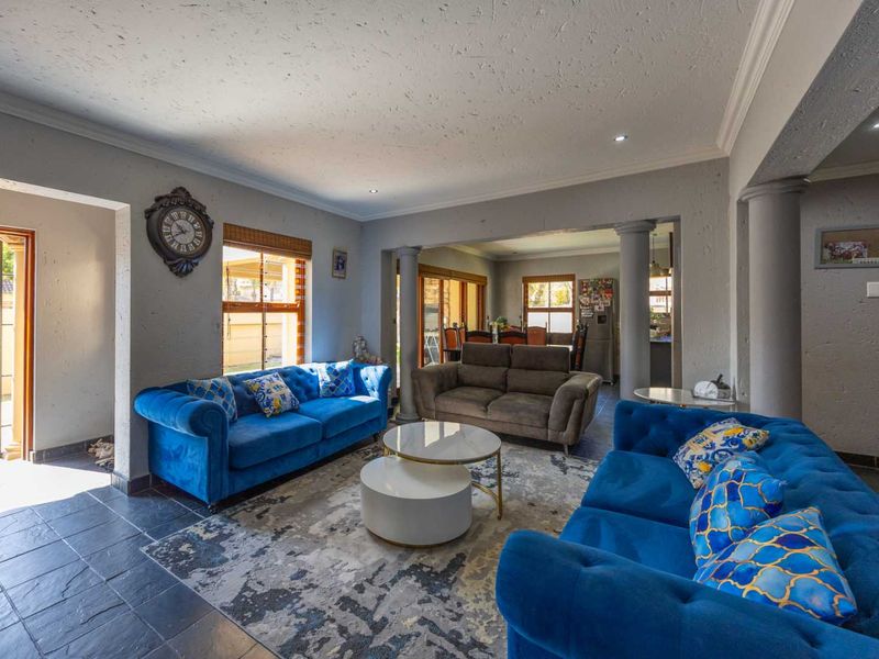 Spacious open-plan living area featuring slate tile flooring, decorative columns, and recessed lighting, with seamless flow to the dining space and outdoor access.