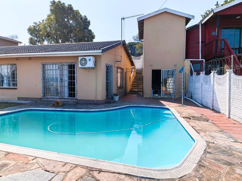 Outdoor pool area featuring a swimming pool with paved surround, security-fitted sliding doors, and perimeter walling with razor wire.