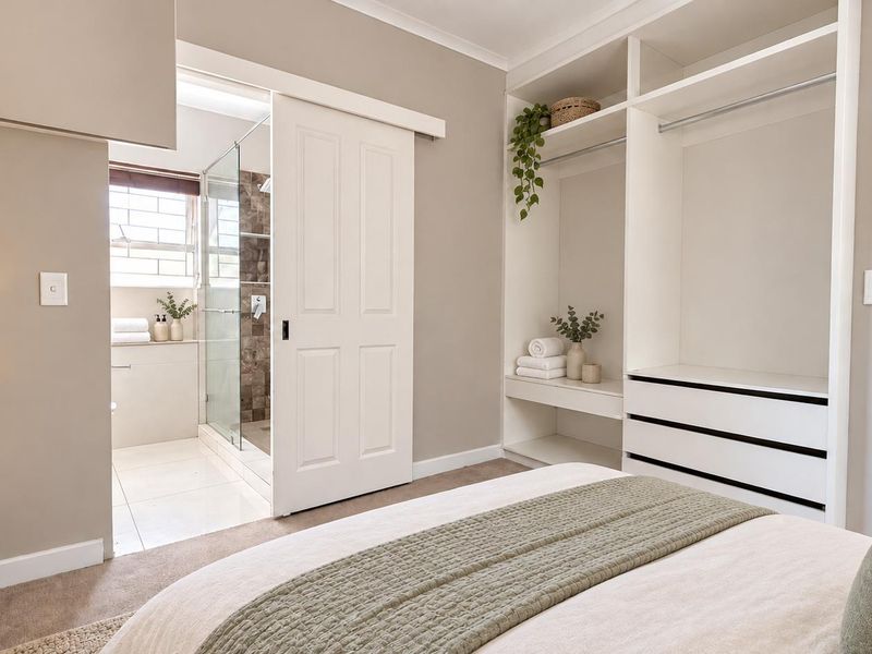A well-appointed bedroom featuring a built-in wardrobe and a convenient en-suite bathroom with a modern glass-enclosed shower.