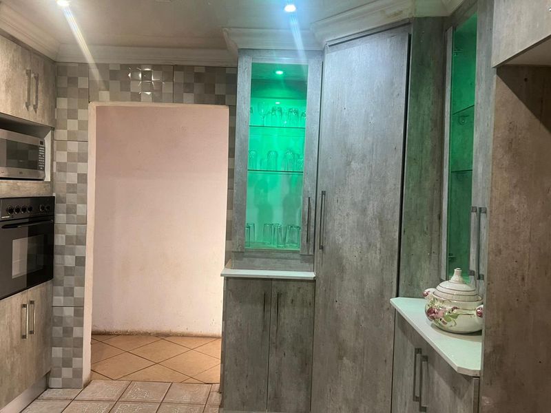 Modern kitchen featuring built-in oven and microwave, tiled backsplash, and custom cabinetry with integrated display lighting.